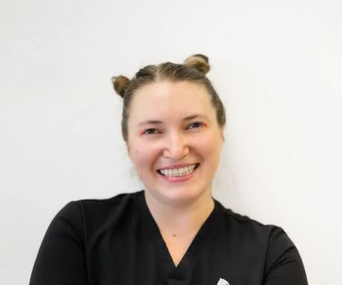 Rachel, a NakedCat Beauty massage therapist, smiling in black scrubs