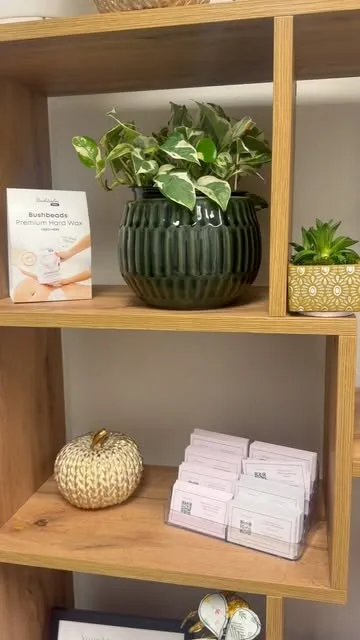 A retail shelf with skincare boxes, plants and a small pumpkin